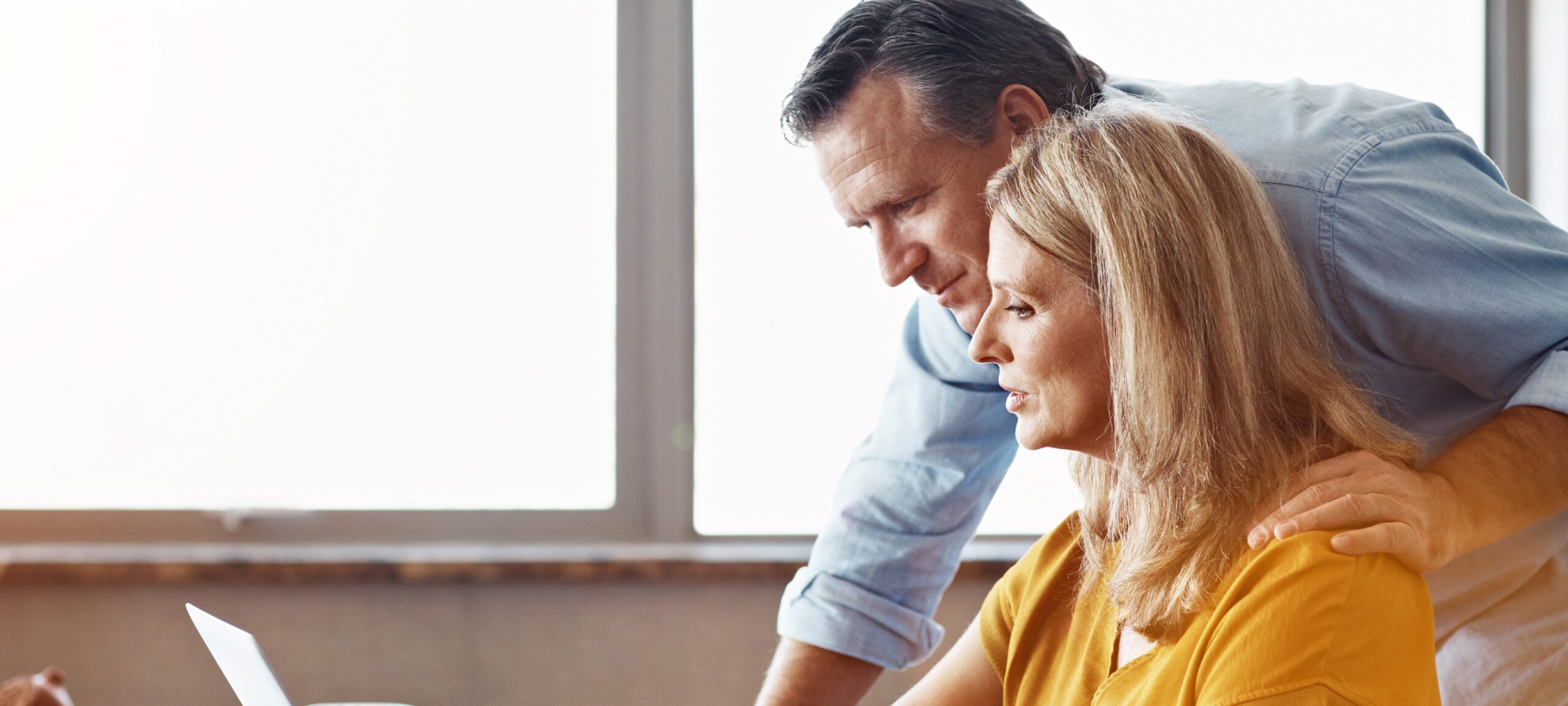 Shot Of A Mature Couple Sitting At Their Dining Room Table Using A Laptop